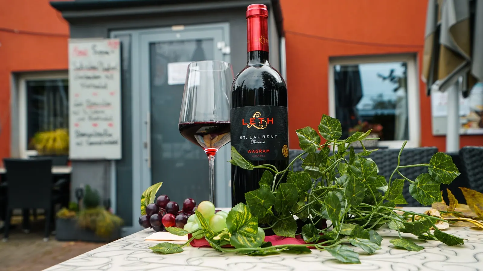 Ein Glas Rotwein und eine Flasche vor dem Eingang des Restaurant Musil.