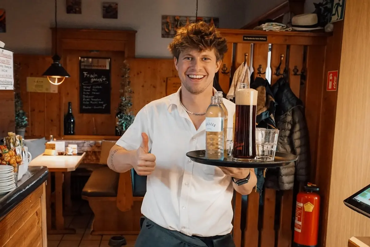 Piere mit einem Getränketablett in der Gaststube.