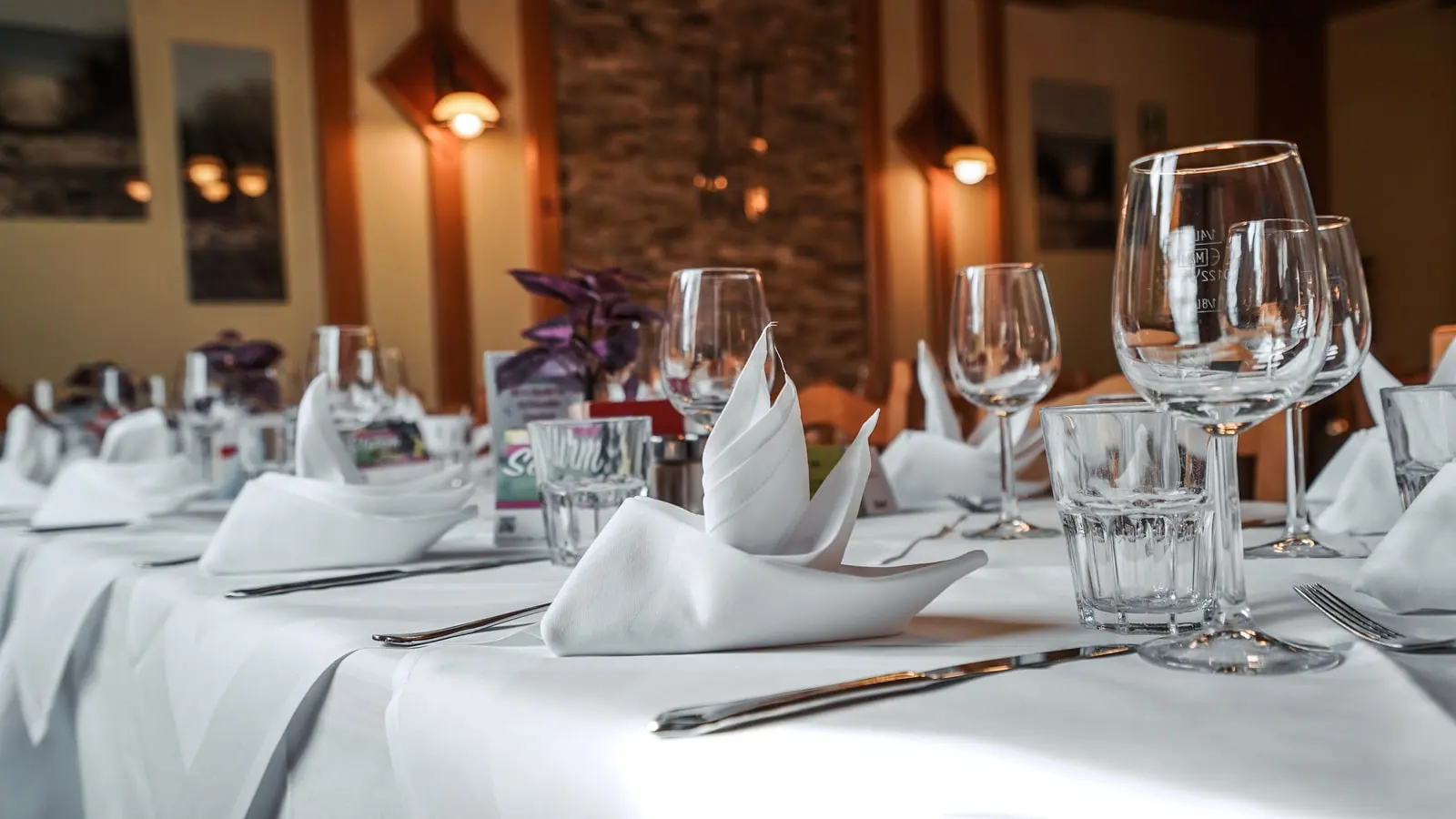 Weiße gefaltete Servietten und Gläser auf einer gedeckten Tafel im Restaurant Musil.