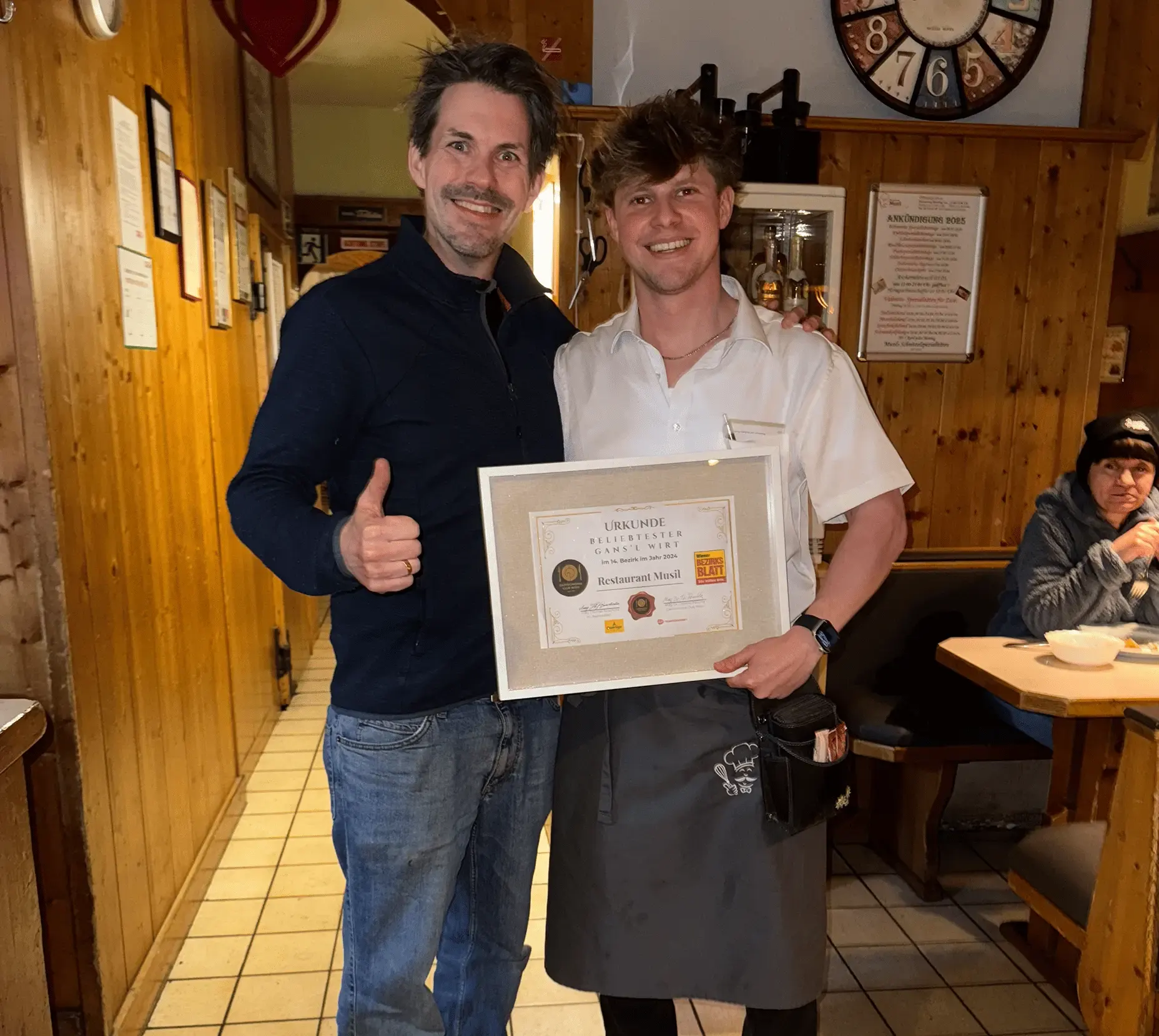 Piere Paukovitsch vom Restaurant Musil hält die Urkunde „Beliebtester Gans’l Wirt im 14. Bezirk 2024“, daneben Obmann Mag. Dr. Thomas Peschta mit erhobenem Daumen.
